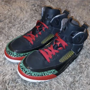 Nike Jordan sneakers svart/röd/grön - Unika Nike Jordan sneakers med svart skinn, röda snören och detaljer i grönt och gult. Snyggt mönstrad tå i grönt och svart, röd sula och ikonisk Jumpman-logga på plösen. Hög modell med coola detaljer och bekväm passform.