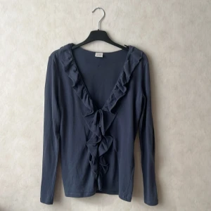 Mörkblå volangtröja  - Supersöt mörkblå långärmad tröja från Esprit med djup v-ringning, volangdetaljer längs ringningen och knyt framtill. Perfekt för dig som gillar en feminin och trendig look. Passar xs-m beroende på hur man vill att den ska sitta. Bra skick. 