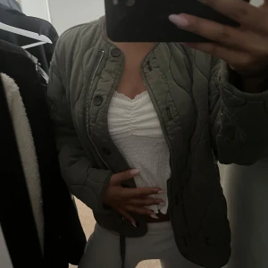 Grön jacka från Zara - Säljer en grön jacka med både dragkedja och knappar framtill. Jackan har en loose passform och har ett snyggt vågigt mönster i quiltningen och rundad krage. Superenkel att styla till olika outfits! 😚❤️