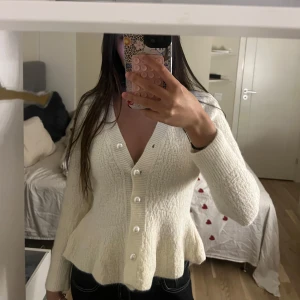 Vit stickad kofta med pärlknappar - Säljer en superfin vit stickad kofta med v-ringning och pärlknappar framtill. Aldig använt💕