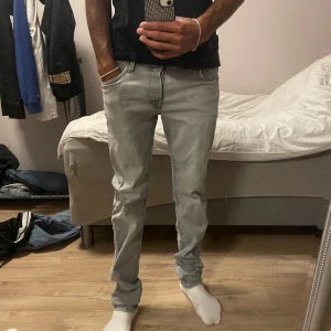 Ljusgrå slim jeans från Jack & Jones - Säljer ett par ljusgrå slim fit jeans från Jack & Jones. Jeansen har klassisk femficksdesign, normal midja och raka ben med en något smalare passform. Tillverkade i mjuk bomullsdenim med snygg tvättad look och diskreta sömmar.