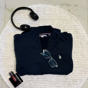 Marinblå half zip tröja U.S. Polo Assn - Snygg marinblå tröja från U.S. Polo Assn med half zip och klassisk logga broderad på bröstet. Tröjan har en enkel, stilren design och är tillverkad i mjuk bomull.  ( är en bit liten i storlek, passar M är lite kort i L ) 