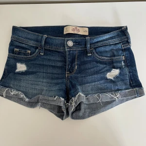 Blå jeansshorts från Hollister - Snygga blå jeansshorts från Hollister med slitna detaljer och fransiga uppvikta kanter. Fint skick. Pris går att diskuteras!