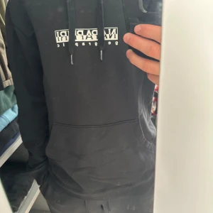 Svart hoodie från Napapijri - Svart hoodie från Napapijri med vit logga på bröstet. Tröjan har huva med snörning och en stor magficka framtill. Mjuk och skön känsla, perfekt för chill dagar. Långärmad och med klassisk passform. Jag är 181cm och 75kg