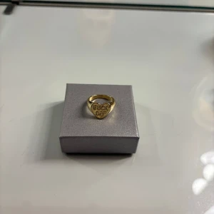 Guldfärgad statementring med text - Guldfärgad ring i hjärtform med ingraverad text framtill. Vet inte vilken storlek ringer är i men skulle gissa på ca 17mm💗