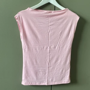 Ljusrosa ärmlös tröja - Supersöt ljusrosa tröja i mjukt material. Toppen är ärmlös med enkel, rak passform och rund halsringning. Perfekt att styla med jeans eller kjol för en fräsch look. Enkel och stilren design som passar till många outfits. Den har små fläckar som vart där ända sedan den köptes. Använd 1 gång. Köptes för 100kr. Pris kan förhandlas.