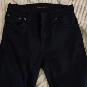 Nudie Jeans pipe led - Snygga svarta jeans från Nudie Jeans Co i klassisk femficksmodell. Jeansen har raka ben, normal passform och är tillverkade i slitstarkt bomullstyg. Perfekta för dig som gillar stilrena och tidlösa jeans med diskreta detaljer.