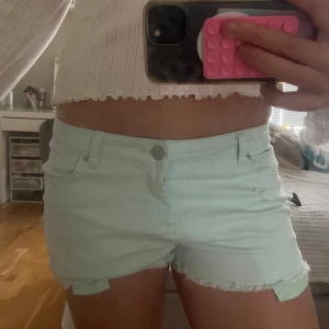 Turkosa jeansshorts - Snygga turkosa unika jeansshorts. Shortsen har låg midja, knapp och dragkedja framtill samt slitna detaljer på ena benet. Storleken står tyvärr inte men skulle säga att det är en s-m