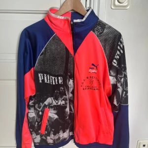 Retro vindjacka från Puma i blått och neon - Säljer en riktigt fet retro jacka med basketmotiv från ett italienskt lag som jag köpt i en second hand butik i Florens. Storleken är small/medium och passformen passar både män och kvinnor men tror främst kvinnor då den har en kortare rygg och ärmar. Skicket är som ny då jag använt den ett fåtal gånger. Går att mötas upp i Barkarby station eller fraktas där du står för frakten. Pris kan diskuteras vid snabb affär