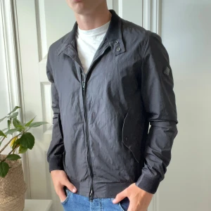 Svart j.lindberg vindjacka  - Perfekt vindjacka inför hösten! Den är hel svart men blev lite konstig ljus i vissa bilder. I nyskick, modellen bär M och är 180,75 kg. 
