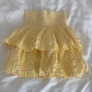 Gul rutig volangkjol från KappAhl - Supersöt gul och vit rutig kjol från KappAhl med smock i midjan och dubbla volanger. Perfekt för soliga dagar och ger en riktigt somrig vibe. 