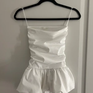 Vit offshoulder volang topp från Zara - Endast använd en gång!!! Supersöt vit off shoulder topp från Zara med volang nedtill. Toppen har en croppad passform och är lätt rynkad för en snygg siluett. Perfekt för sommarens alla tillfällen när du vill sticka ut lite extra.