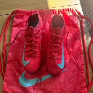Nike Mercurial rosa fotbollsskor - Säljer ett par Nike Mercurial fotbollsskor i ett bra skick. Dom är använda två gånger men har tyvärr blivit försmå. När man köper skorna får man med en helt ny elit bag. Dom är i stolek 38. Nypris: 3099kr