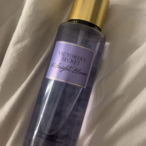 Victoria's Secret Midnight Bloom mist - Fräsch och blommig body mist från Victoria's Secret i doften Midnight Bloom. Flaskan är genomskinlig med lila toner och har en snygg guldig kork. Perfekt att spraya på för en fräsch känsla hela dagen.
