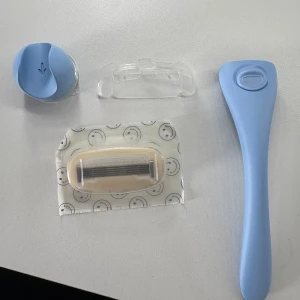 Blå rakhyvel från Estrid  - Säljer en ljusblå rakhyvell från estrid. Medföljer ett extra rakblad, ett väggfäste och ett skydd för bladet. 