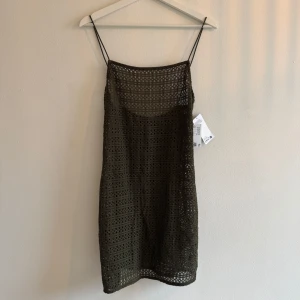 Olivgrön virkad kortklänning H&M - Snygg olivgrön kortklänning från H&M i virkad bomull. Klänningen har tunna axelband och ett genombrutet mönster som ger en cool och luftig känsla. Perfekt för varma dagar och enkel att styla med sneakers eller sandaler. kort strandklänning i stickad bomull med virkad look. Klänningen har supersmala axelband och djupringad rygg. Ofodrad.