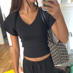 Svart topp från Vero Moda - Svart topp från Vero Moda med v-ringning och korta, vida ärmar. Snygg och enkel design som passar till mycket. Mjukt material och figurnära passform! 