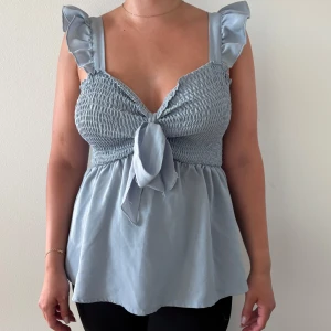 Ljusblå blus med volang - Endast använd 1 gång. Jag är 163 cm lång och blusen är storlek S/XS (stretch). !