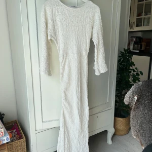 Vit långklänning från NA-KD - Superfin vit långklänning från NA-KD med strukturerat tyg och långa ärmar. Klänningen har en snygg snörning i sidan och en figurnära passform. Använd ungefär 2 gånger!🩷🩷
