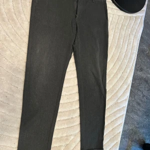 Mörkgrå kostymbyxor med smal passform - Snygga mörkgrå kostymbyxor med smal passform och klassisk design. Byxorna har raka ben, diskret dragkedja och hällor för bälte. Perfekta för en clean och stilren look.