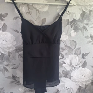 Vintage linne från veromoda - Supersnygg svart linnetopp från Vero Moda i storlek XS. Toppen har smala axelband, omlott-skärning framtill och band i ryggen som man kan knyta till en rosett 💕 Vintage i strl 34. Pris kan alltid diskuteras ☺️