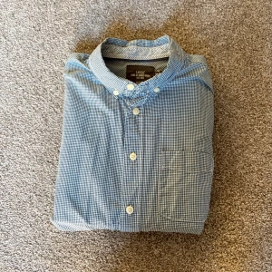 Blårutig skjorta från L.O.G.G. H&M - Snygg blårutig skjorta från L.O.G.G. H&M i bomull. Klassisk modell med knappar framtill, bröstficka och button down-krage. Perfekt till jeans eller chinos för en chill och stilren look.