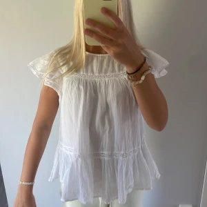 Vit volangblus med spetsdetaljer - Jätte jätte söt blus från Gina🥰Använd ett fåtal gånger och säljer för att den ej kommit till användning, storlek 158/164 men rätt så stor i storleken så passar till s🥰🩷