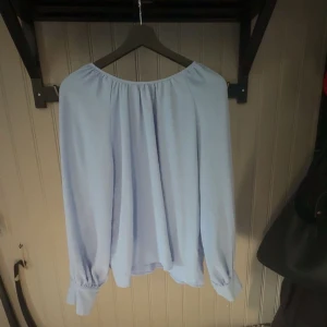 Ljusblå blus - Säljer en ljusblå blus med avslappnad passform, långa ärmar . Blusen har en rundad halsringning med lätt rynkning som ger en snygg och flowy look. Perfekt för dig som gillar stilrena och luftiga toppar i storlek M men funkar lika bra till S från only