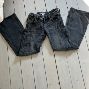 Grå bootcut jeans från Gina Tricot - Snygga grå jeans från Gina Tricot i bootcut-modell. Jeansen har klassiska fem fickor, silverfärgade knappar och en cool tvättad look. Perfekta för dig som gillar en avslappnad men trendig stil. Storlek 146. pris kan diskuteras