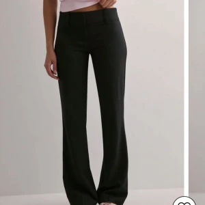 Svarta flare kostymbyxor - Snygga svarta flare kostymbyxor och låg midja. Byxorna har klassisk passform, bälteshällor och stängs med dragkedja och två knappar. Mycket använda men bra skick och lite slitna längst nere