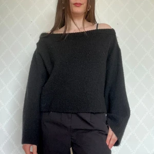 Svart offshoulder stickad tröja - Svart stickad tröja med offshoulder och långa ärmar🥰Ganska liten i storleken så funkar bra även om man har storlek S