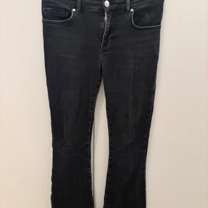 Svarta low flare jeans XS - Snygga svarta jeans med låg midja och flare-ben. Modellen är tight upptill och släpper ut nedtill för en cool siluett. Jeansen har klassiska fickor fram och bak, samt dragkedja och knapp. Längd 31. Perfekta till sneakers eller boots.