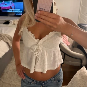 Vit croppad linnetopp med knyt - Supersöt vit linnetopp med volangkant och knyt framtill.🤩