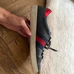 Gucci skor  - Snygga svarta sneakers från Gucci med klassiska Gucci märket, strl 44. Väldigt bra skick skulle jag säga då jag endast har använt dem 5 gånger. Köpte dem inför ett bröllop och använde dem under helgen och tappade sedan bort dem i garderoben i en dust bag så lite dammiga men orkar inte vispa bort det utan här visar man allt. Nu är dem hittade och kan bli dina för ett lysande pris. 