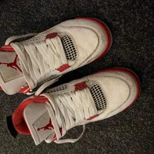 Nike Air Jordan 4 Retro Vit/Röd - Säljer ett par Nike Air Jordan 4 Retro sneakers i vitt skinn med röda och svarta detaljer. Skorna har klassisk mesh på sidorna, tjock vadderad plös med Jumpman-logga och robust sula med röd Nike Air-detalj. Perfekta för dig som gillar ikoniska och sportiga sneakers. Äkta ingen box tyvärr pris går att diskuteras kan kolla om jag hittar kvittot 