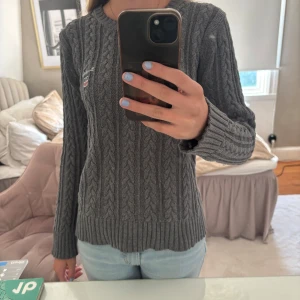 Poppis kabel stickad  - Supersnygg grå kabelstickad tröja från Bondelid med broderad logga på bröstet. Orginal pris 700