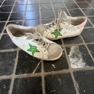 Golden Goose sneakers - Golden Goose sneakers i vitt skinn med en grön  Perfekt för dig som gillar statement-detaljer och coola kontraster.