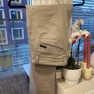 Beige chinos från NN07, stl 32/34 - Snygga beige chinos från NN07 med klassisk passform. Byxorna är tillverkade i mjuk bomull. Storlek 32/34