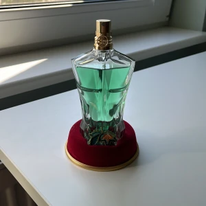 Le Beau Paradise Garden Eau de Parfum - Säljer en cool parfym från Jean Paul Gaultier, Le Beau Paradise Garden Eau de Parfum. Flaskan är formad som en manlig torso i transparent grönt glas med en guldfärgad spraykork. Volymen är 70 ml. Kommer med en röd sammetsbas.