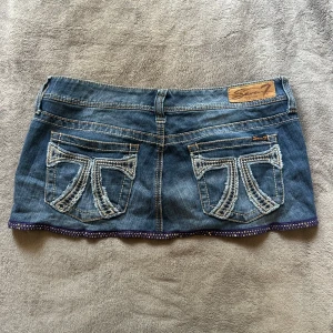 Jeanskjol Lågmidjad kort detaljer - Supersnygg kort Lågmidjad jeanskjol. Skulle säga storlek M. Coola detaljer på fickorna!                       Midjemått: 43 cm
