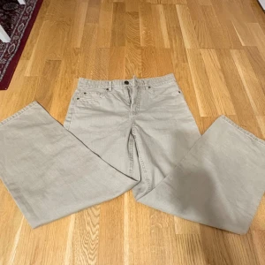 Beige wide jeans från Denim 1953 - Snygga beige jeans från Denim 1953 i storlek 38. Modellen har breda ben och klassisk femficksdesign. Tillverkade i ett hållbart bomullsmaterial som känns både mjukt och slitstarkt. Perfekta för dig som gillar en avslappnad och trendig stil.