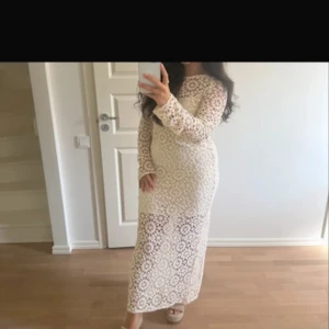 Beige klänning  - Superfin långklänning i vit spets med snyggt cirkelmönster. Klänningen har långa ärmar, rund halsringning och en öppen rygg. Slits baktill för extra vibe. Perfekt för dig som vill sticka ut med en romantisk och trendig look. Etikett kvar, ny endast testad nypris 869kr slutsåld på hemsidan 