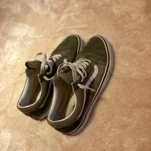 Vans Old Skool sneakers - Säljer ett par klassiska Vans Old Skool sneakers i olivgrönt med vit sula och vit sidostrip. Stolrke 42,5, erbjudandet går ut 5e september