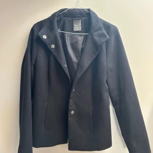 Svart jacka från Primark - Stilren svart jacka från Primark med klassisk krage och snygga knappar framtill. Jackan har en rak passform och är helfodrad för extra komfort. Perfekt för dig som vill ha en enkel men elegant look.