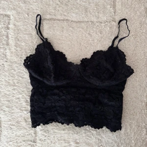 Svart spetsig croppad linnetopp - Säljer en svart croppad linnetopp med tunna axelband och vacker spetsdetalj över hela toppen. As snygg och jätte bekväm 