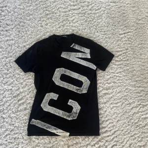  Dsquared2 T-shirt  - Säljer en svart t-shirt från Dsquared2 med stor vit 'ICON'-text diagonalt över framsidan. Den sitter som XS! Klassisk rund hals och korta ärmar. Kontakta mig vid minsta fundering.
