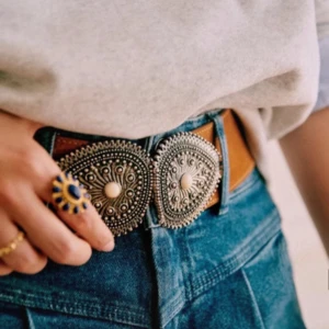 Brunt bälte med dekorativt spänne från Sezane  - Snyggt brunt bälte i skinn från By Malene Birger med bred design och två stora, silverfärgade spännen med detaljerad mönstring. Perfekt accessoar för att lyfta din outfit.