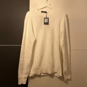 Vit stickad tröja  - Helt ny vit stickad tröja. Fräsch färg med ett snyggt stickat räfflat mönster. Aldrig använd därav inga defekter (prislapp sitter kvar). Hör av er vid funderingar 🙌