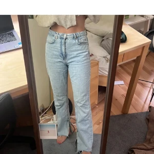 Ljusblå bootcut jeans med slits  - Säljer ett par ljusblå jeans med bootcut passform och hög midja. Jeansen har slits med slitningar längst ned. Använda en gång då de är för stora. Jeansen har legat i garderoben några månader därför finns de ej på hemsidan längre. 