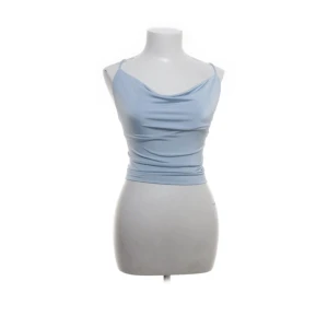 Ljusblå croppad linnetopp från BikBok - Säljer en ljusblå croppad linnetopp från BikBok med tunna axelband och snygg snörning i ryggen. Toppen har en draperad framsida och är perfekt för varma dagar. Superfin att styla till ett par snygga byxor eller kjol!